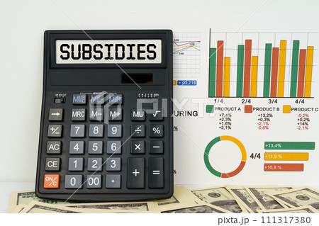 On the table are financial reports, dollars and a calculator with the inscription - Subsidies On the table are financial reports, dollars and a calculator with the inscription - Subsidies 111317380