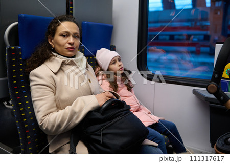 Beautiful family, mother and daughter sitting by passenger window in a high speed train commuting from one city to other. Beautiful family, mother and daughter sitting by passenger window in a high speed train commuting from one city to other. 111317617
