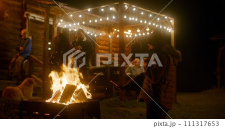 Couple of travelers drinks tea, laughs and warms near the fire 111317653