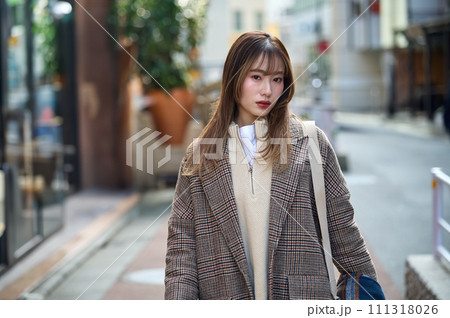 散歩するコートを着たロングヘアーの若い女性 111318026