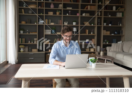 Young smiling businessman in glasses working on-line using laptop Young smiling businessman in glasses working on-line using laptop 111318310