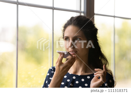 Close up young woman recording audio voice message, holding smartphone 111318371