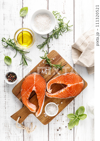 Fresh raw salmon steaks on a board with ingredients for cooking, top view 111320521
