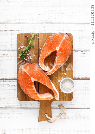 Fresh raw salmon steaks on a board with ingredients for cooking, top view 111320535