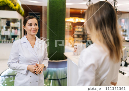 Two doctors standing on hospital corridor discussing patient diagnose. Young physician consulting woman colleague standing in meeting room. Concept of healthcare. 111321361