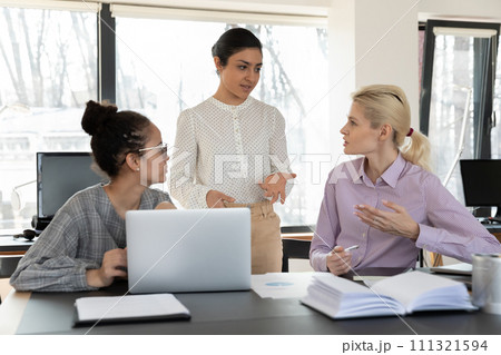 Multiethnic female workers brainstorm at workplace together Multiethnic female workers brainstorm at workplace together 111321594