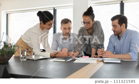 Diverse colleagues work on financial documents at meeting 111321595