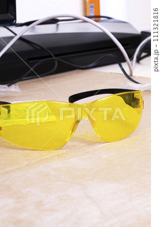 Engraver and yellow protection glasses on the desktop Engraver and yellow protection glasses on the desktop 111321816