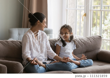 Young Indian woman her cute daughter meditating at home 111321859
