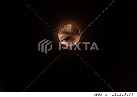 Curious little kid eye looking into box through round hall 111323674