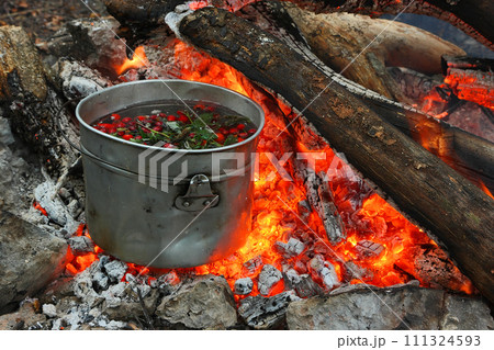 Touristic bowler on burning coals. Cooking hot drinks from the hips and forest berries on the touristic fire. 111324593
