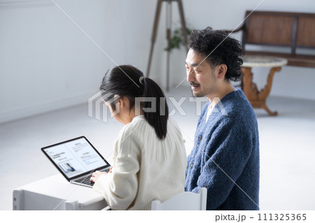 ノートパソコンを操作する小学生と教えるパパ 111325365