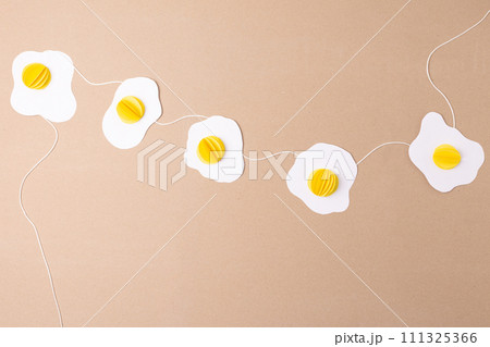 simple fried eggs paper craft hanging from a string, easter decoration concept, top view 111325366