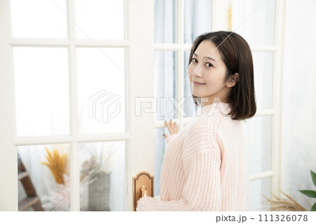 ピンクのセーターを着て振り向く若い女性 111326078