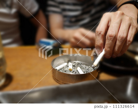 紙たばこを吸っている人が灰皿に灰を落とす 紙たばこを吸っている人が灰皿に灰を落とす 111326614