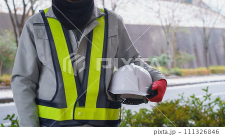 ネックウォーマーで防寒対策をする作業服の男性と積雪風景 111326846