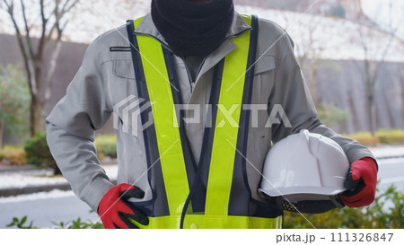 ネックウォーマーで防寒対策をする作業服の男性と積雪風景 111326847