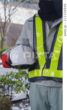 ネックウォーマーで防寒対策をする作業服の男性と積雪風景 111326848