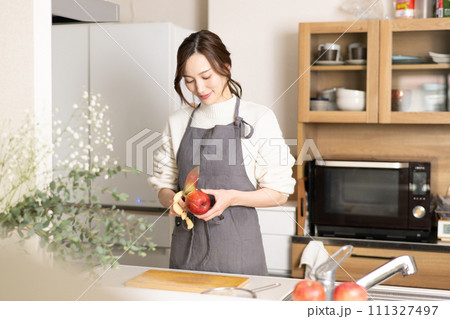 キッチンで林檎の皮を剥く若い女性 キッチンで林檎の皮を剥く若い女性 111327497