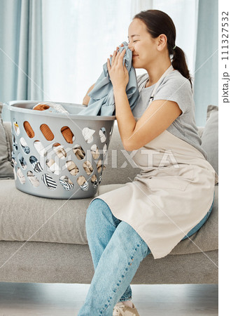 Clean laundry, happy woman and smelling fabric, fresh scent of clothes and washing basket of linen textile at home. Young, smile and asian person, housekeeping service and domestic cleaning lifestyle 111327532