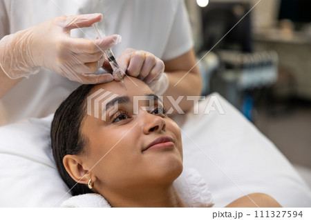 Young dark-skinned woman having a session of mesotherapy Young dark-skinned woman having a session of mesotherapy 111327594