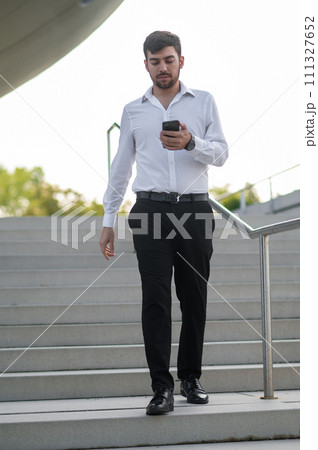 Young businessman with a phone in hand looking confident Young businessman with a phone in hand looking confident 111327652
