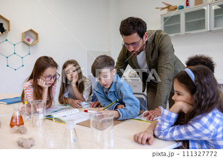Man teacher with kids during chemistry lesson in school classroom. Man teacher with kids during chemistry lesson in school classroom. 111327772