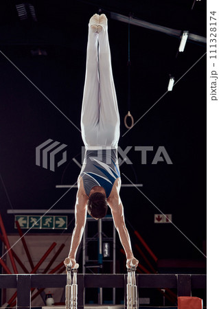 Strong man training for fitness in gym, cardio sports exercise at stadium at night and sport workout for health and wellness in dark arena. Young athlete person doing gymnastics in competition Strong man training for fitness in gym, cardio sports exercise at stadium at night and sport workout for health and wellness in dark arena. Young athlete person doing gymnastics in competition 111328174