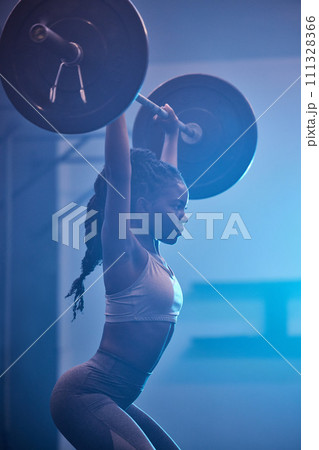 Weightlifting focus, motivation and fitness workout mindset of woman lifting weights at a gym. Female from Kenya working out, sports exercise and strong sport training at a health and wellness club Weightlifting focus, motivation and fitness workout mindset of woman lifting weights at a gym. Female from Kenya working out, sports exercise and strong sport training at a health and wellness club 111328366
