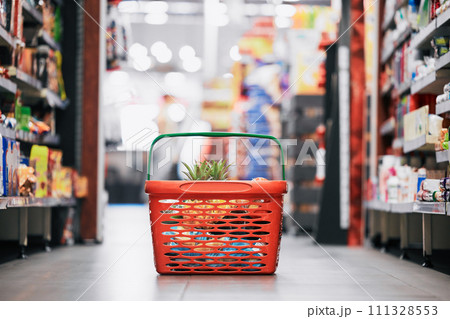 Supermarket, shopping and store grocery basket on floor of retail food shop for eating, drinking and health. Pineapple, apple and fruit product sale at mall food market for a customer or consumer Supermarket, shopping and store grocery basket on floor of retail food shop for eating, drinking and health. Pineapple, apple and fruit product sale at mall food market for a customer or consumer 111328553