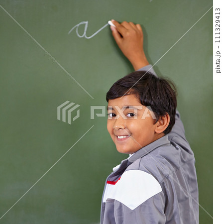 Portrait, chalk and boy writing on a board for child development, confidence and art for learning. Academic, creative and kid student drawing on a blackboard in the classroom with face and excited 111329413