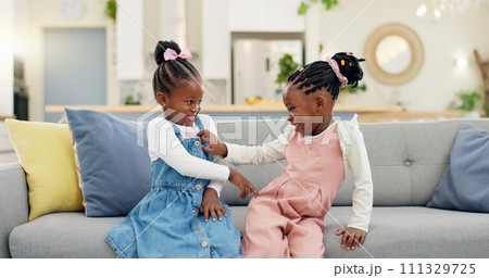 Kids, play and couch in a home with poke, smile and happy from sibling bonding together. House, lounge sofa and daughter friends with game and girl friendship with fun and youth in a living room 111329725