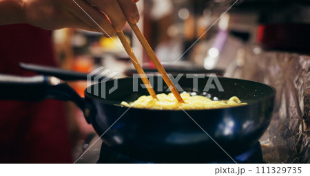 Cooking, restaurant and person with noodles in pan on gas stove at market for meal preparation, eating and cuisine. Culinary, flame and closeup of chopsticks to prepare lunch, dinner and supper 111329735