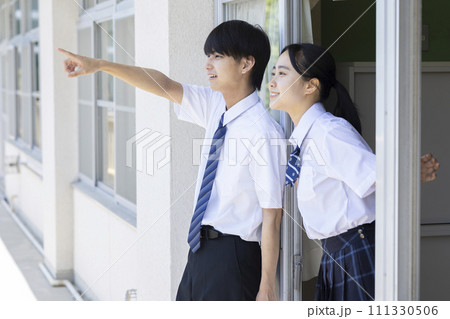 学校の廊下で話をする高校生 111330506