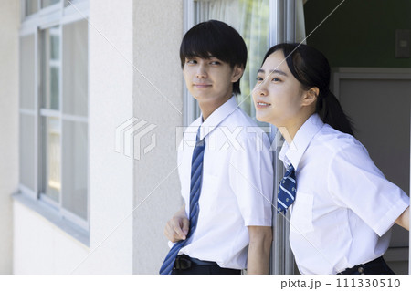 学校の廊下で話をする高校生 111330510