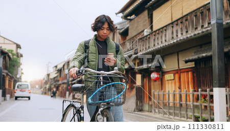 Bicycle, cellphone and man riding by building for exercise or transportation to college academy. Fitness, phone and young male student driving a bike to university for carbon footprint by houses. Bicycle, cellphone and man riding by building for exercise or transportation to college academy. Fitness, phone and young male student driving a bike to university for carbon footprint by houses. 111330811