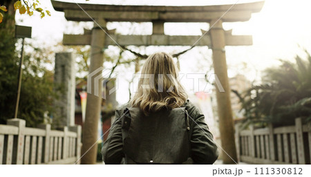 Woman, nature and torii gate in Kyoto with backpack, tourist and back with traditional history. Architecture, japanese culture and shinto shrine in woods with sculpture, memorial and monument 111330812