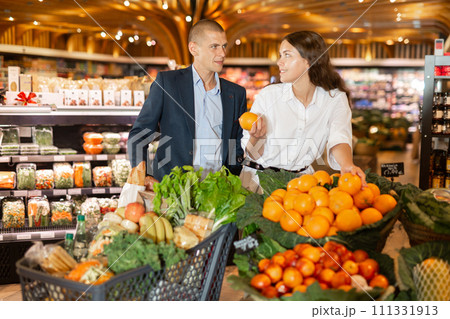 Happy young couple with a grocery cart in the supermarket shooses tangerines 111331913