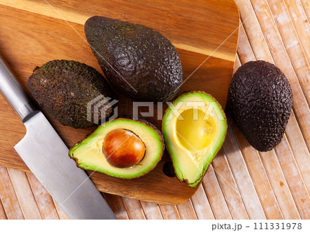 Whole and sliced avocados on wooden board Whole and sliced avocados on wooden board 111331978