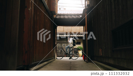 Bicycle, travel and man riding by building for exercise or transportation to college academy. Fitness, backpack and young male student driving a bike to university for carbon footprint by houses. 111332032
