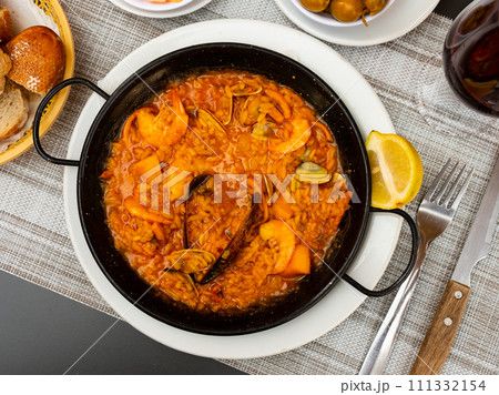 Spanish rice dish paella tinted with saffron. Prepared with olive oil and seafood Spanish rice dish paella tinted with saffron. Prepared with olive oil and seafood 111332154