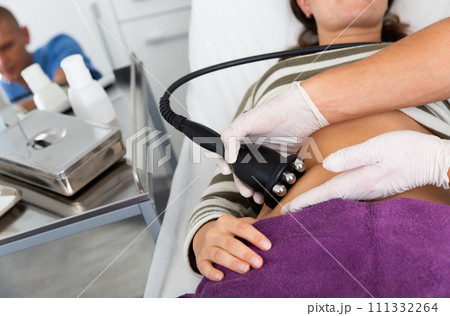 Woman getting radiofrequency lifting procedure on abdomen Woman getting radiofrequency lifting procedure on abdomen 111332264