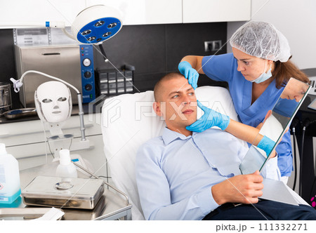 Woman beautician consulting male client before facial treatment Woman beautician consulting male client before facial treatment 111332271