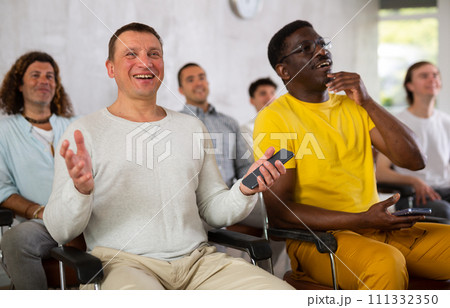 Group of men listening to lecture in auditorium cheerfully Group of men listening to lecture in auditorium cheerfully 111332350