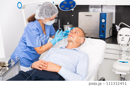 Man receiving cosmetic facial injection in clinic Man receiving cosmetic facial injection in clinic 111332451