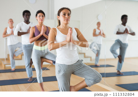 Latin american girl in Eka Pada Pranamasana during group yoga training 111332804