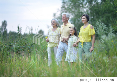 Elderly couple with their daughter and granddaughter walking in a field 111333140