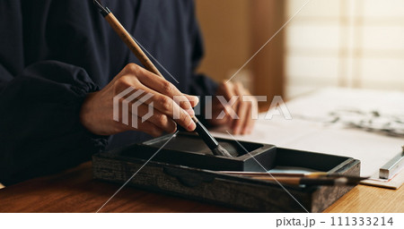 Hands, brush in ink for writing and Japanese calligraphy or ancient script for art and inkstone. Asian creativity, black paint and vintage tools, paintbrush and person with traditional stationery Hands, brush in ink for writing and Japanese calligraphy or ancient script for art and inkstone. Asian creativity, black paint and vintage tools, paintbrush and person with traditional stationery 111333214