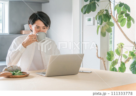 朝食を食べながらパソコンを使う男性 朝食を食べながらパソコンを使う男性 111333778
