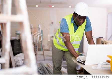 African american engineer checks a home renovation plan on a laptop African american engineer checks a home renovation plan on a laptop 111333919